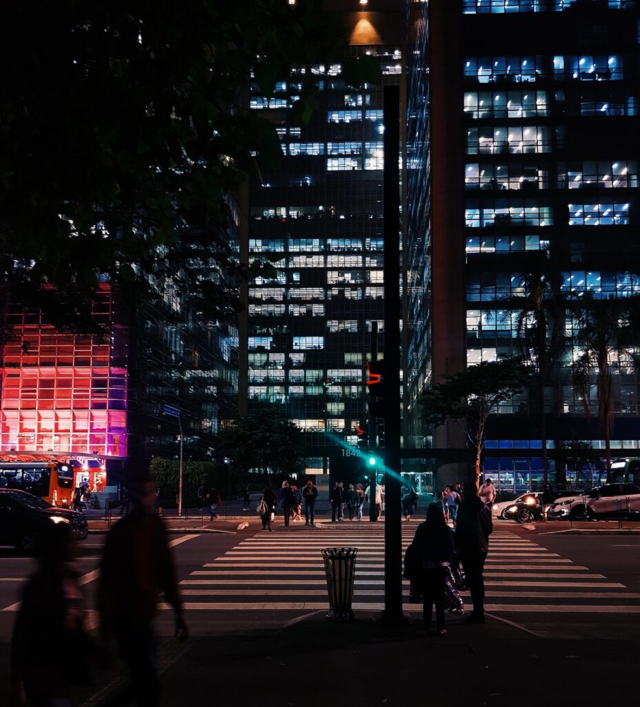 Fotografia noturna de edifícios envidraçados da Avenida Paulista.