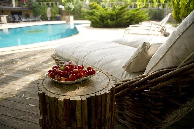 Cadeira de descanso ao lado de uma cesta com cerejas frescas, localizada na área da piscina.