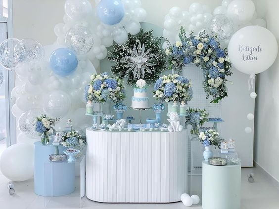 Decoração da mesa feita com flores e balões, com as cores branca e azul.