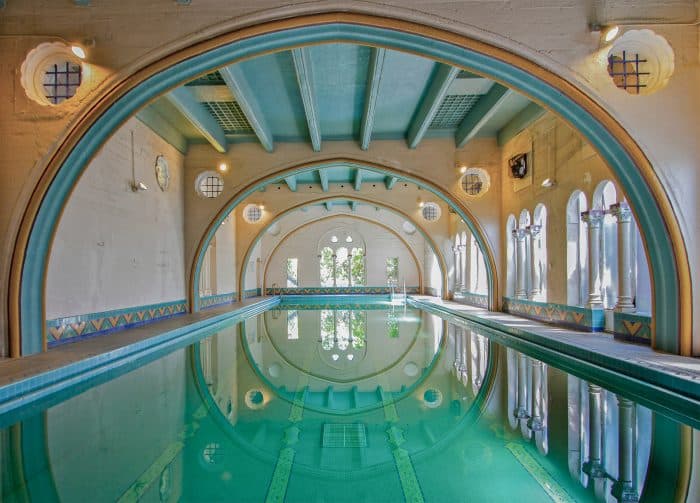 Vista de piscina coberta em um ambiente arqueado, com adornos que lembram uma casa de banho oriental.