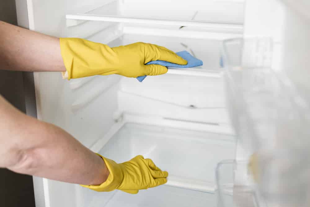 Limpando a geladeira antes de começar a organizá-la.