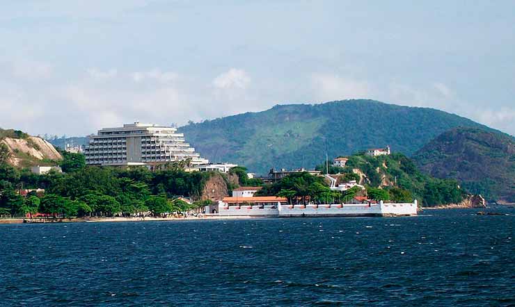 Praia de Gragoatá, o Forte de São Domingos de Graoatá e prédios e montanhas ao fundo.
