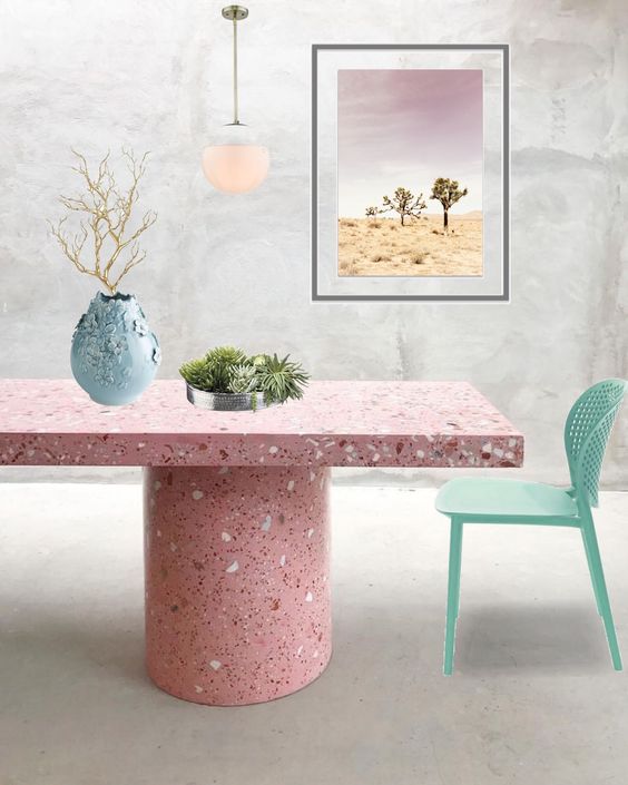 Mesa da sala de jantar feita com granilite em tons de rosa, com uma cadeira verde água ao lado e objetos de decoração.
