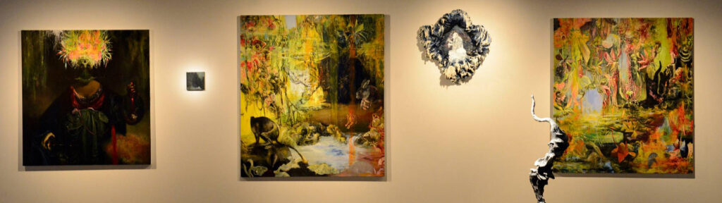 Três pinturas, uma do lado da outra, entre duas delas existe um quadro com uma moldura rústica. 