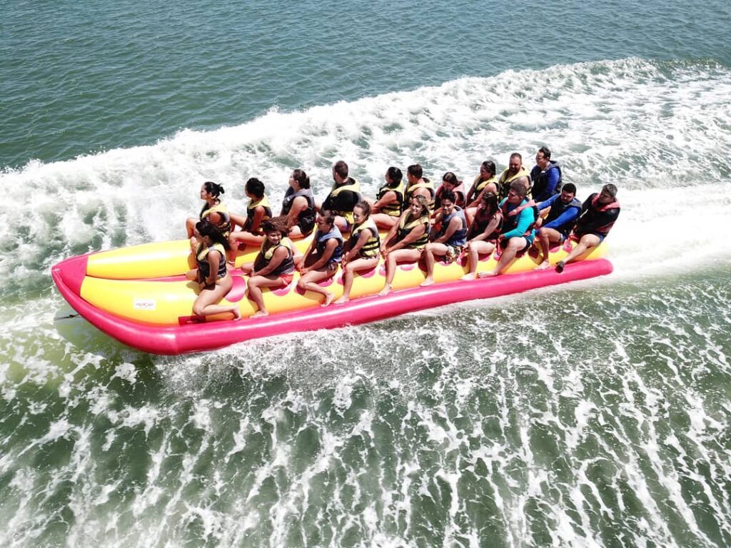 Banana boat com dez pessoas em cada lado da banana fazendo o passeio no mar.