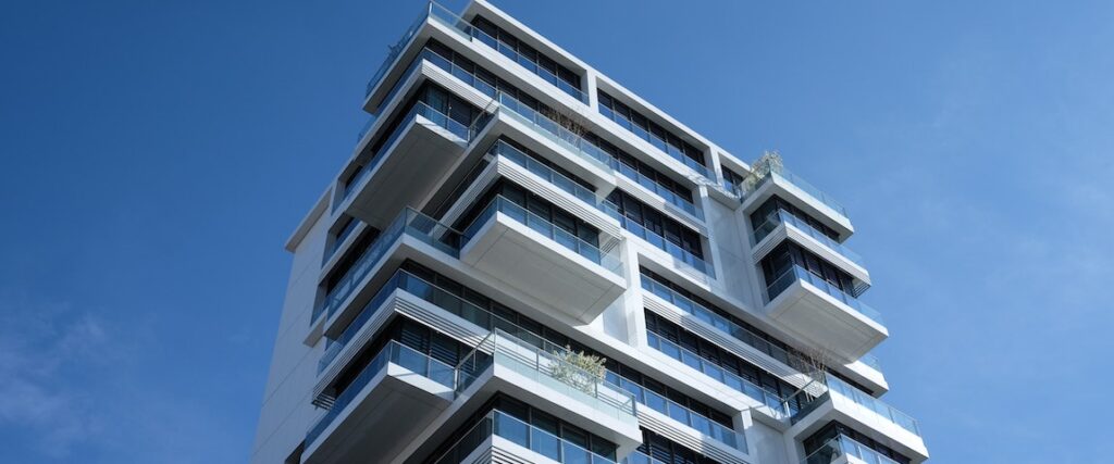 Fachada de um prédio com terraços com guarda-corpo de vidro.