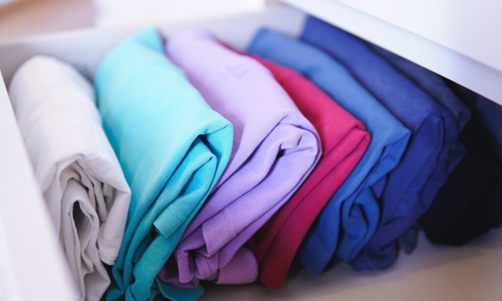 Camisetas separadas por cor e dobradas em formato de retângulo.