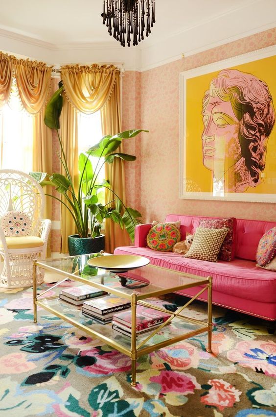 Sala de estar com sofá rosa, tapete estampado e quadro.