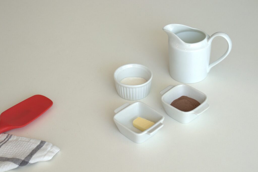 Imagem dos quatro ingredientes necessários para a calda de chocolate, dispostos em uma bancada.