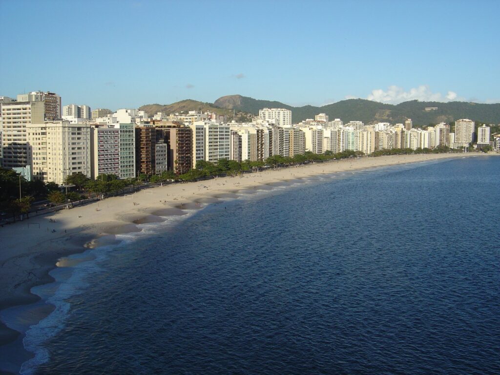 Icaraí, rodeada por prédios residenciais, com uma extensa faixa de areia e um mar limpo e azul.