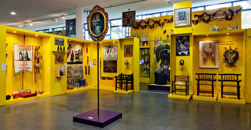 Fotografia de espaço de exposições permanentes, com quadros, esculturas e objetos ocupando toda a extensão das paredes.