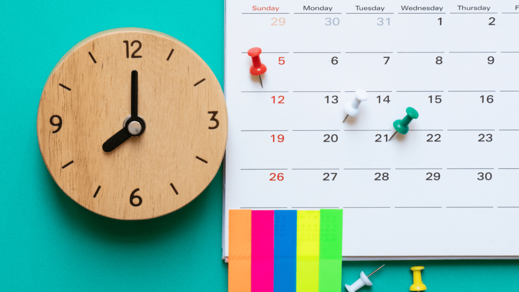 Relógio de madeira e um calendário mostrando como é importante definir horários para suas tarefas.